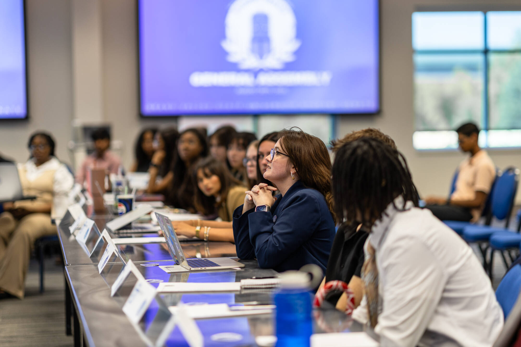 Student senators sitting in a row at general assembly, one student speaking.